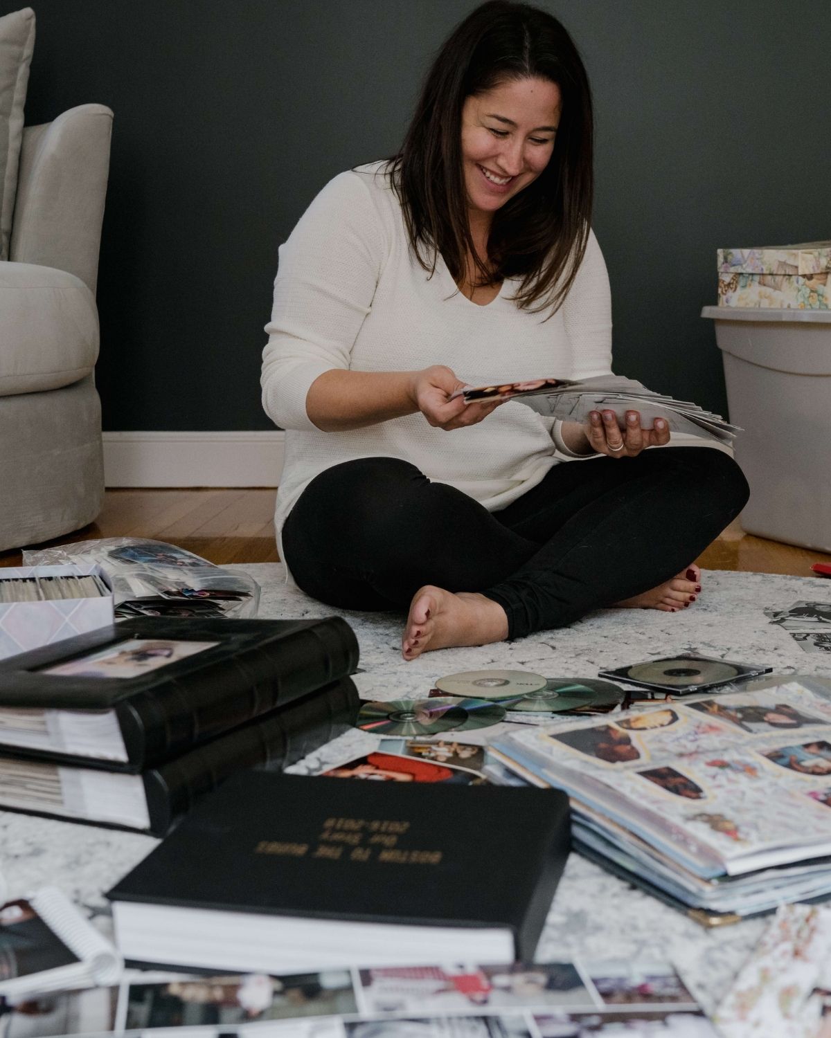 woman sitting on floor looking through sentimental old photographs and scrapbooks
