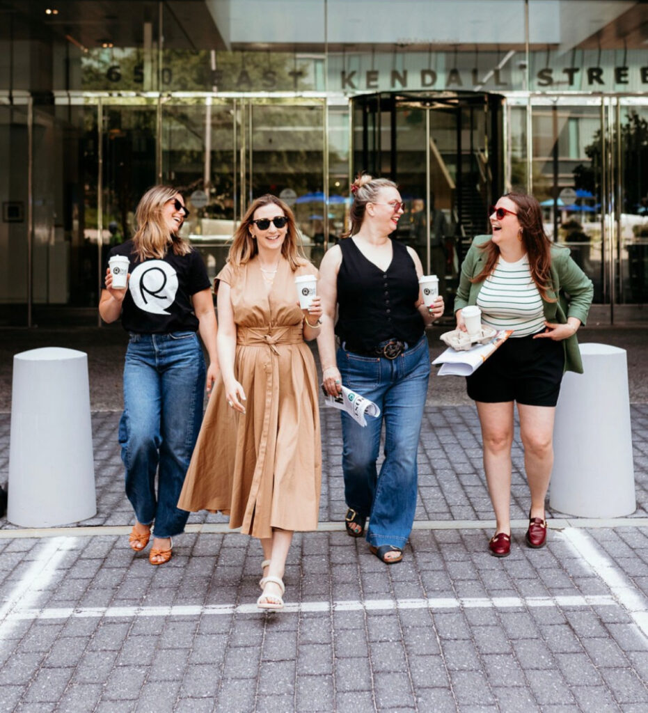 retail playground team members walking on boston street. Founder Allison Yee with along with 3 other women smiling and laughing while holding retail playground coffee mugs. 