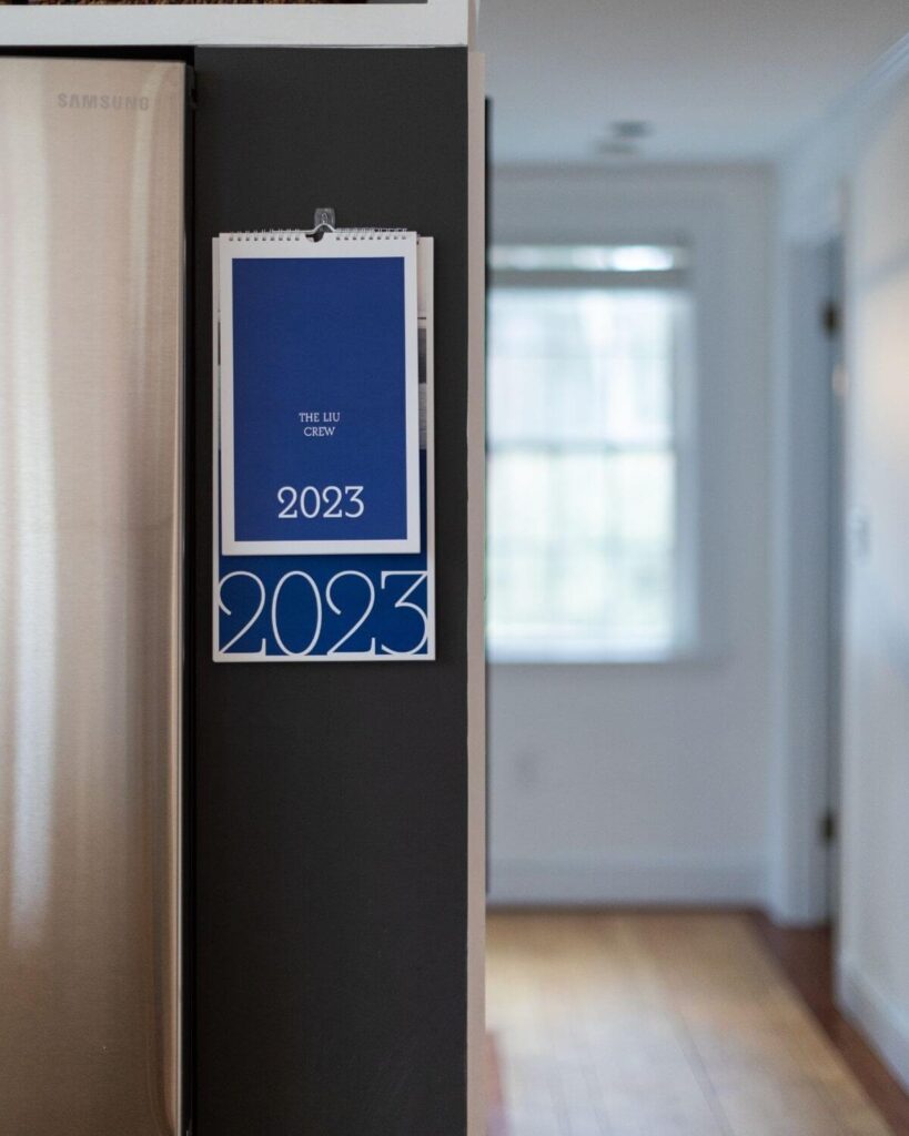 Pinhole Press large wall calendar on wall behind small wall calendar to compare the size of the photo calendar offerings. On wall in kitchen next to fridge. 