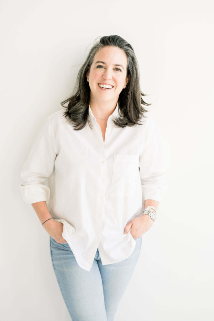 Ellie Rineck founder of Pepper Books and A Day in Her Life Podcast standing in white shirt on white background