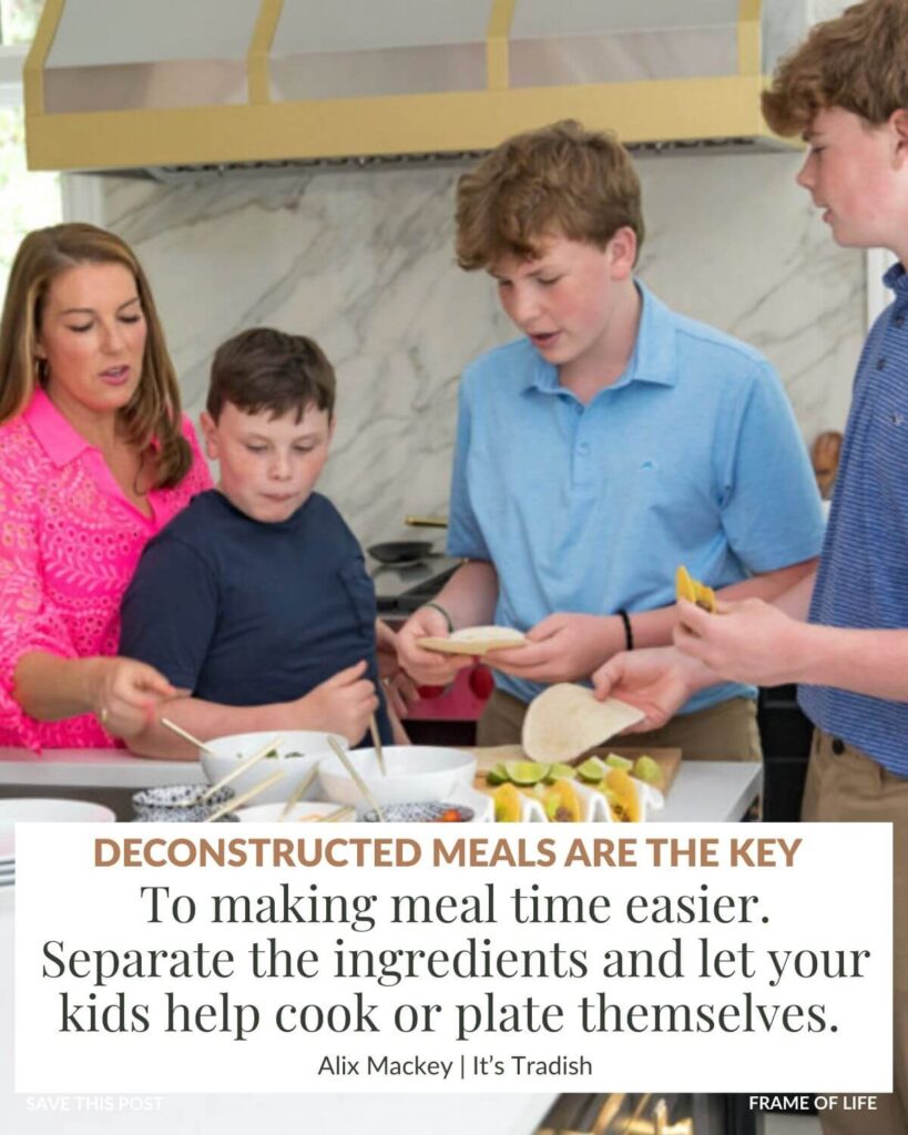 Alix Mackey, founder of Its Tradish, with her 3 boys in her kitchen around the island prepping an easy kid friendly meal - taco dinner. The text box says: Deconstructed meals are the key to making mealtime easier with kids. Separate the ingredients and let your kids help cook or plate themselves.