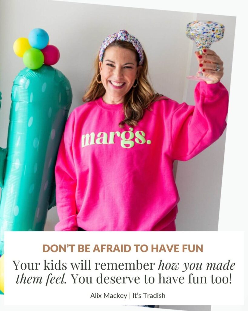Alix Mackey, founder of It's Tradish wearing a pink sweatshirt that says Margs on it. Holding a margarita glass standing next to a balloon cactus smiling. Cinco de mayo sprinkle of fun with a text box that says: Don't be afraid to have fun. Your kids will remember how you made them feel. You deserve to have fun too!