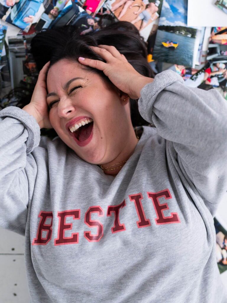 bestie photo organizer kiera liu pulling her hair out looking overwhelmed while laying on a pile of photos